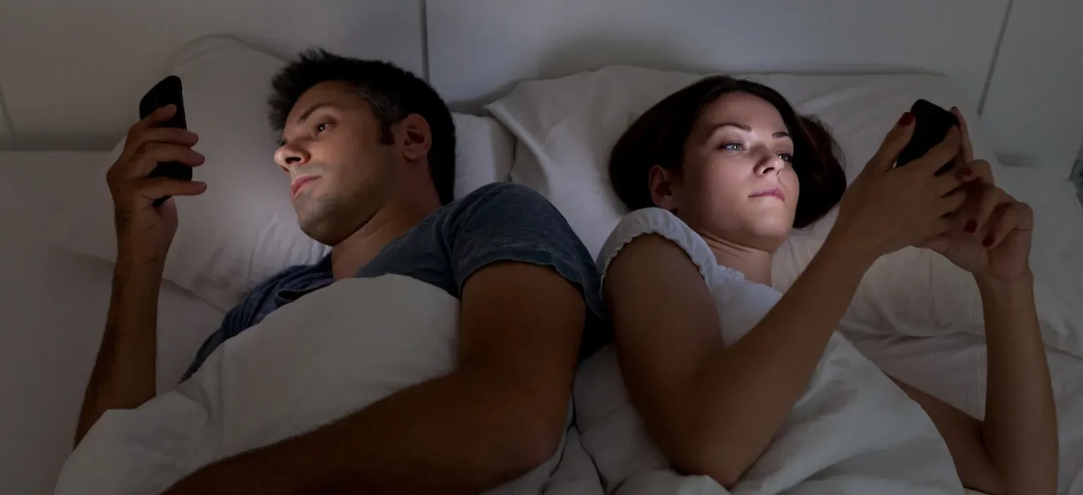 Couple using cell phone at the bed