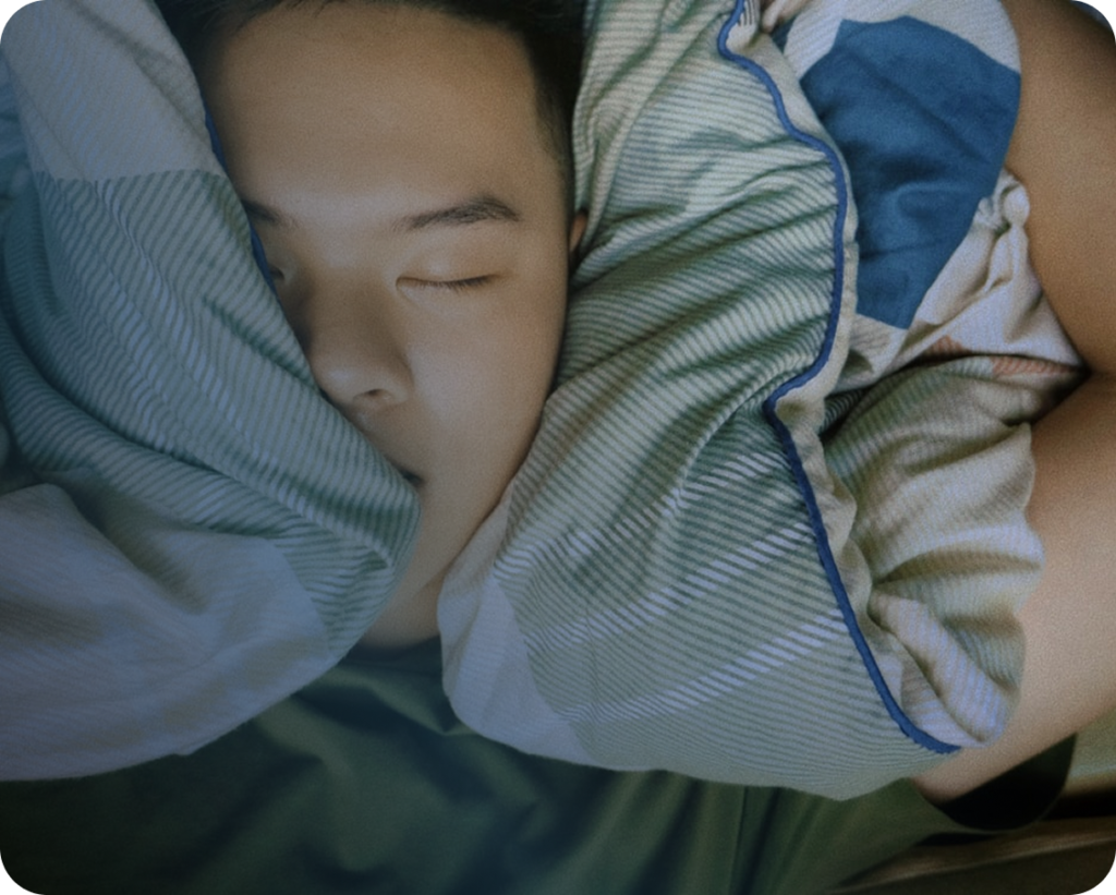 A man sleeping with pillow covering his mouth
