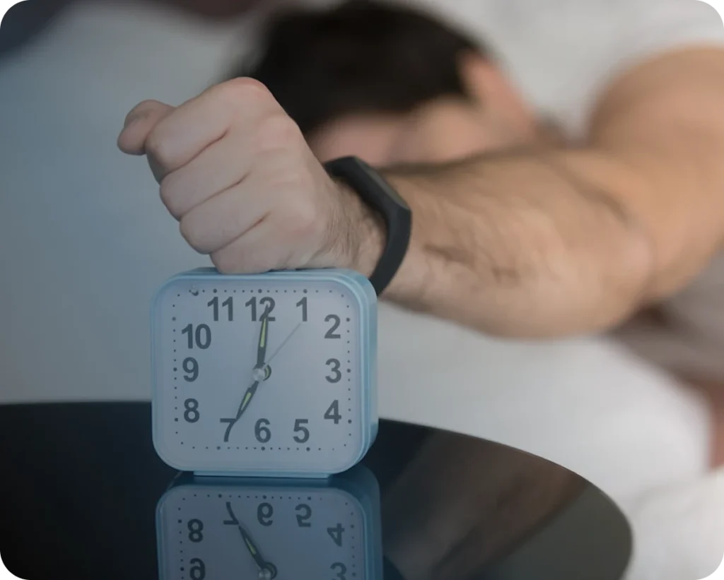 A man turning off his alarm clock in the morning.